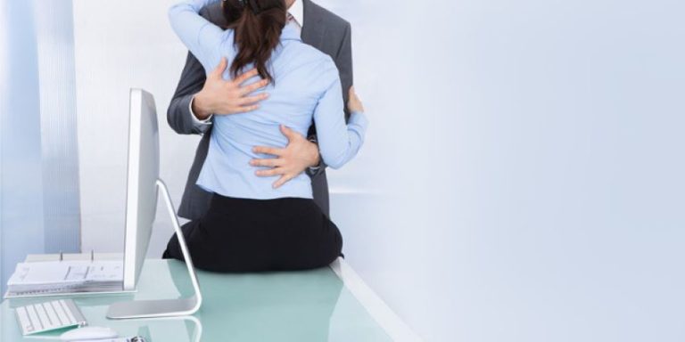 pareja abrazándose en una oficina sobre un escritorio