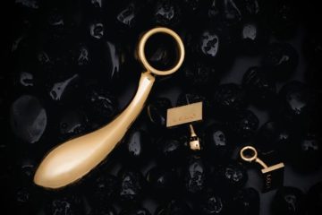 juguete erótico artesanal en oro sobre fondo oscuro, símbolo de lujo y exclusividad