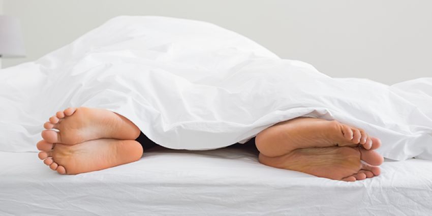 Pareja en la cama bajo una sábana blanca simbolizando la falta de deseo sexual o anafrodisia