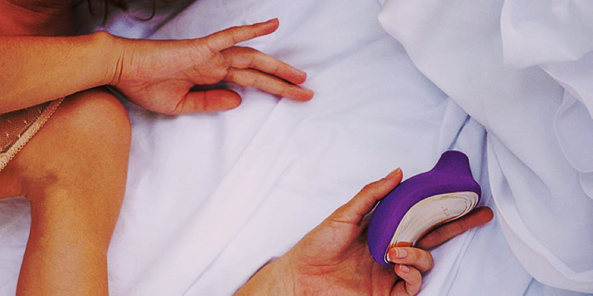 persona sosteniendo un succionador de clítoris en la cama