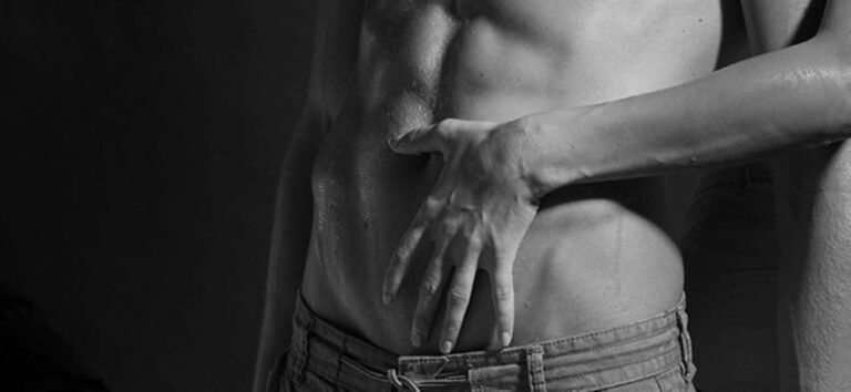 Mano de mujer acariciando el abdomen de un hombre cerca de la cintura