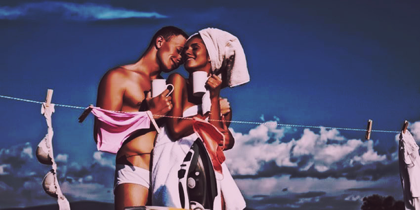 Pareja sonriente compartiendo un momento íntimo en casa mientras tienden la ropa