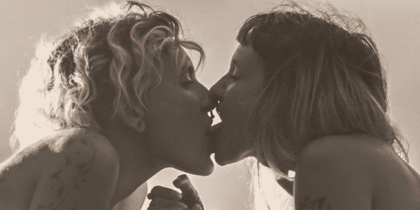 dos mujeres besándose en una escena íntima en blanco y negro