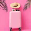 Maleta rosa de viaje sobre fondo tropical utilizada para ilustrar las ofertas Prime de juguetes sexuales LELO