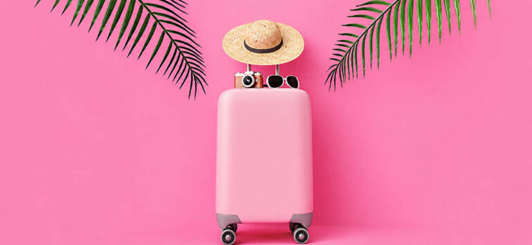 Maleta rosa de viaje sobre fondo tropical utilizada para ilustrar las ofertas Prime de juguetes sexuales LELO