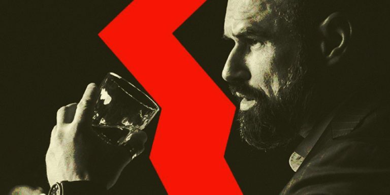 Hombre observando con intensidad mientras sostiene un vaso en un bar