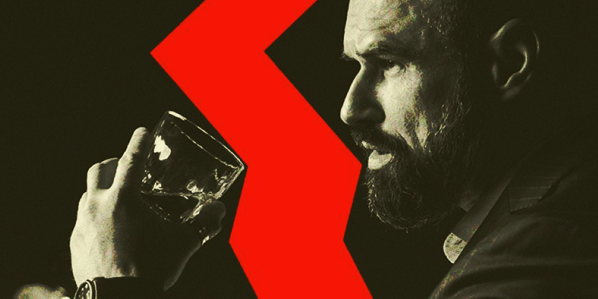 Hombre observando con intensidad mientras sostiene un vaso en un bar