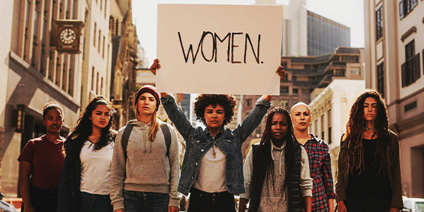 mujeres manifestándose por el Día Internacional de la Mujer con un cartel women