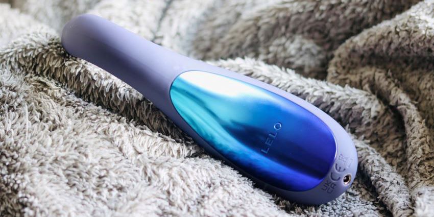 LELO ENIGMA Double Sonic sobre una manta mostrando su acabado Cyber Purple