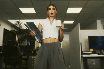 Mujer en oficina moderna con café y documentos en la mano