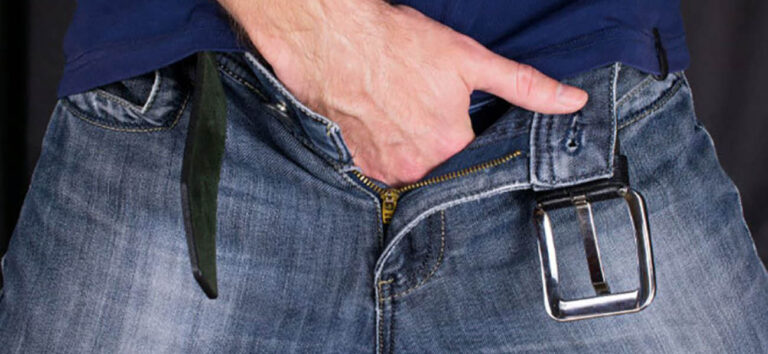 Hombre introduciendo la mano en el pantalón como representación de la preocupación por el tamaño del pene