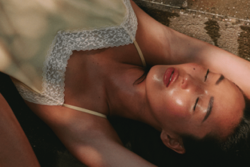 Mujer recostada con los ojos cerrados bajo la luz cálida del atardecer