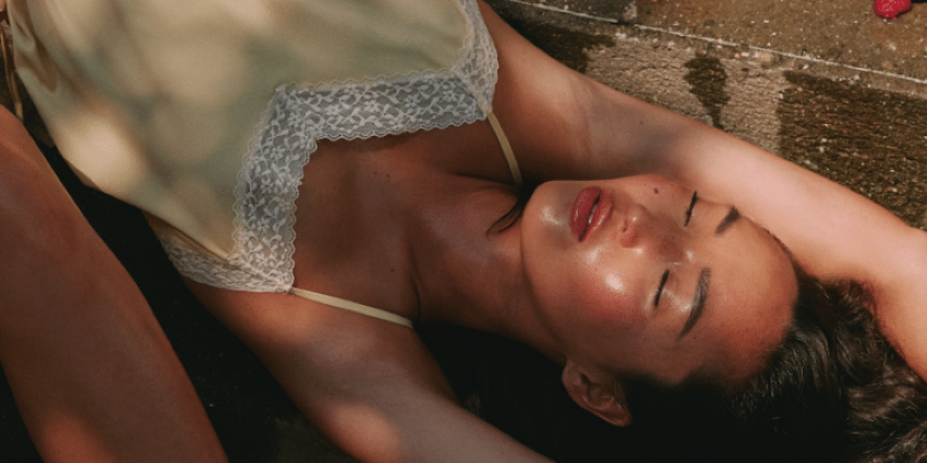 Mujer recostada con los ojos cerrados bajo la luz cálida del atardecer