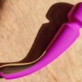 Vibrador wand recargable en color fucsia con diseño curvo y cabezal amplio