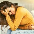 mujer con dolor por endometriosis sentada sujetando el abdomen