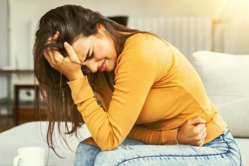 mujer con dolor por endometriosis sentada sujetando el abdomen