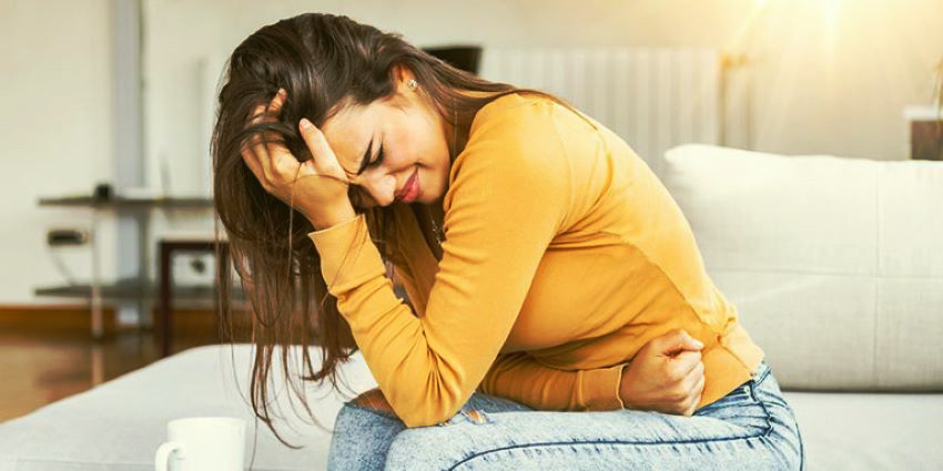 mujer con dolor por endometriosis sentada sujetando el abdomen