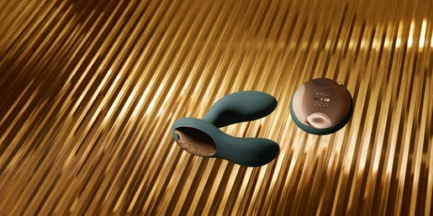 Juguete sexual de silicona y mando sobre fondo dorado, ejemplo de cuidado y limpieza