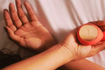 mujer sosteniendo un vibrador de silicona en la mano sobre la cama