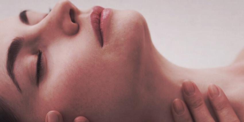 Mujer relajada con los ojos cerrados durante un momento íntimo en la perimenopausia