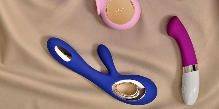 juguetes sexuales de diferentes tipos como vibrador rabbit y vibrador curvado sobre tela beige