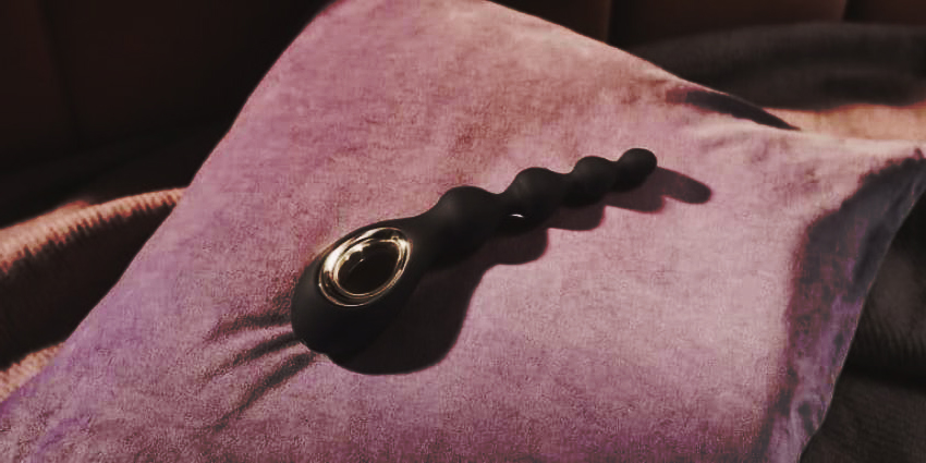 juguete anal para principiantes de silicona negra con diseño ergonómico sobre cojín