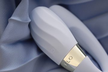 Vibrador con textura para parejas TIANI Twist de LELO sobre tela satinada azul