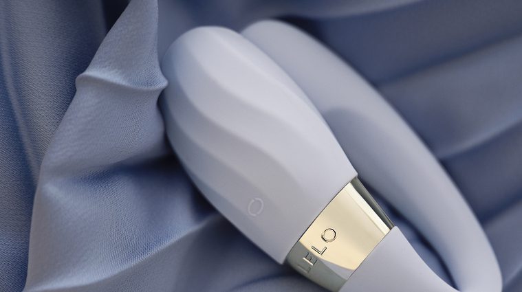 Vibrador con textura para parejas TIANI Twist de LELO sobre tela satinada azul