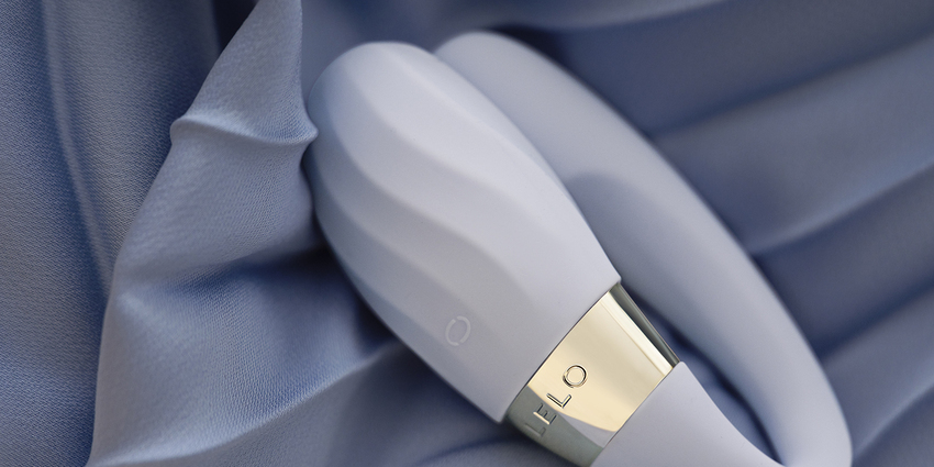 Vibrador con textura para parejas TIANI Twist de LELO sobre tela satinada azul