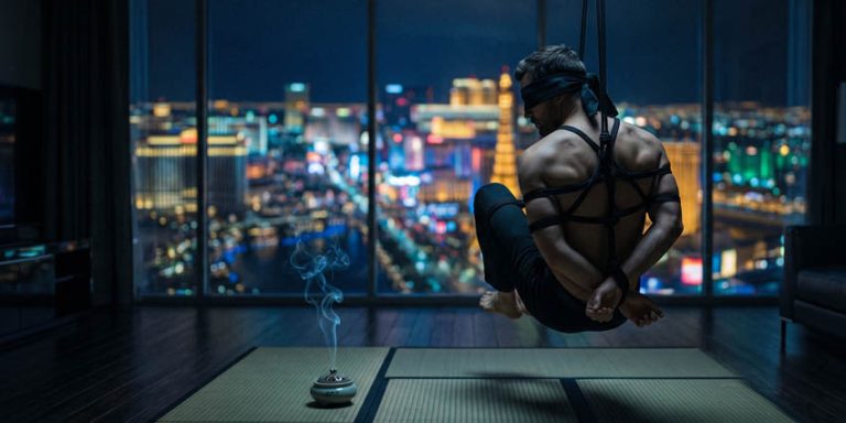 Hombre suspendido con cuerdas shibari frente al Strip de Las Vegas de noche