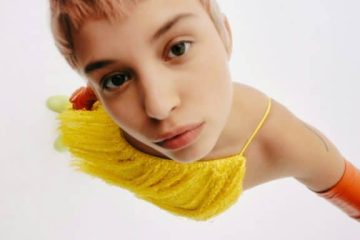 Persona apoyada sobre un tejido amarillo en una imagen artística relacionada con relajación, bienestar sexual y alivio del estrés.