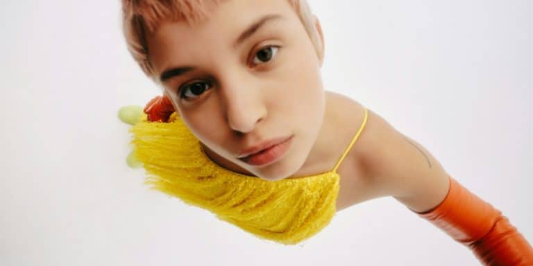 Persona apoyada sobre un tejido amarillo en una imagen artística relacionada con relajación, bienestar sexual y alivio del estrés.