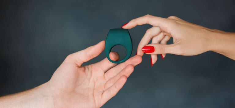 Manos sosteniendo un anillo para el pene de silicona verde oscuro