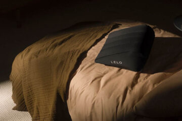 Almohada sexual hinchable de LELO colocada sobre una cama en un dormitorio elegante y discreto