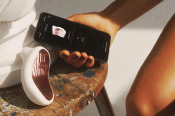 Succionador de clítoris LELO SONA con control mediante app junto a un smartphone mostrando la interfaz de control del juguete
