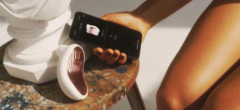 Succionador de clítoris LELO SONA con control mediante app junto a un smartphone mostrando la interfaz de control del juguete