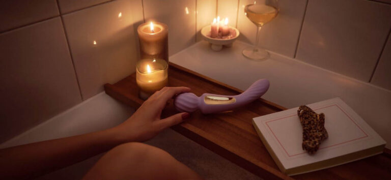 Vibrador sumergible utilizado en una bañera junto a velas para ilustrar el uso de juguetes resistentes al agua